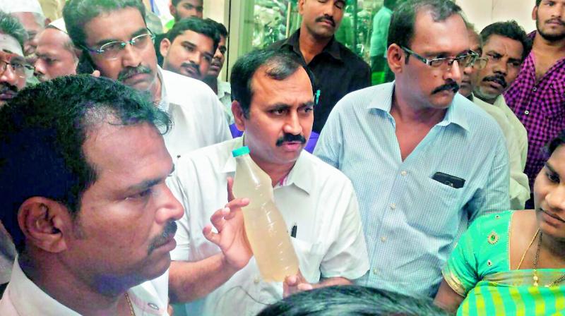 Mangalagiri MLA Alla Rama Krishna Reddy shows the impure water which is been supplied to Tadepalli town.