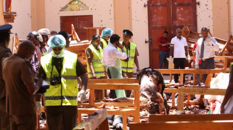 Sri Lankan security personnel walk past debris next to a dead body slumped over a bench following an explosion in St Sebastians Church in Negombo, north of the capital Colombo, on April 21, 2019. (Photo: AFP)