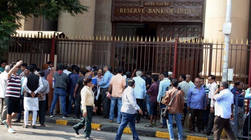 People wait outside the Reserve Bank to deposit their banned currency notes in Mumbai on Monday. (Photo: PTI)