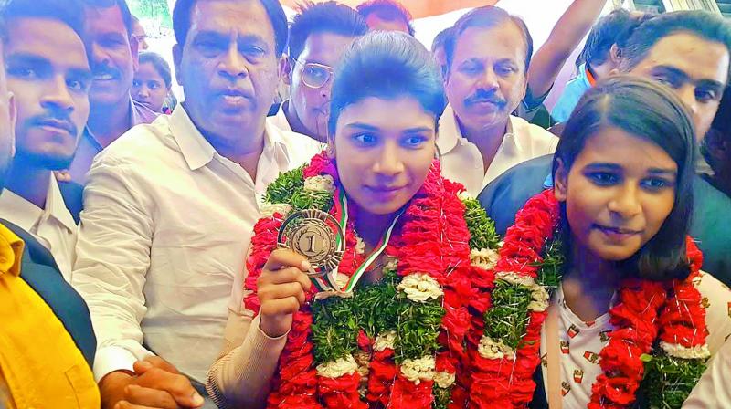Boxer Nikhat Zareen (centre) shows off her gold medal after arriving in Hyderabad on Monday. She is flanked by sister Afnan (right), a state level badminton player, and Sports Authority of Telangana State chairman Allipuram Venkateshwar Reddy (left).
