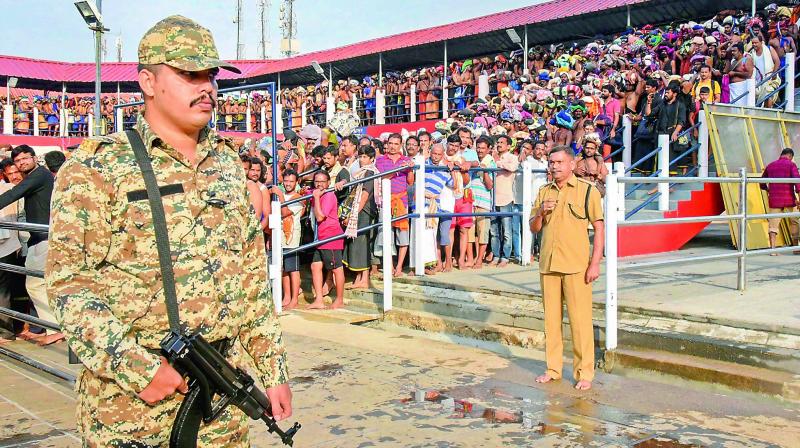 A police commando keeps vigil as devotees wait to offer prayers at Lord Ayyappa temple on the first day of Malayalam month of Vrischikom. (Photo: PTI)