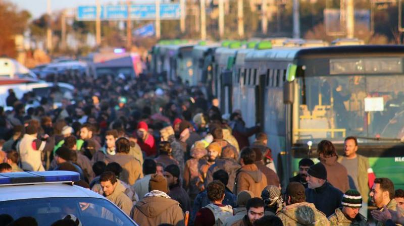 Residents gathered near green government buses as they hold their belongings for evacuation from eastern Aleppo, Syria. (Photo: AP)