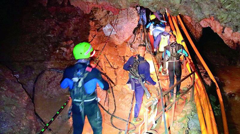 Thai rescue team members walk inside a cave where 12 boys and their soccer coach are trapped since June 23, in Mae Sai, Chiang Rai province, Thailand.