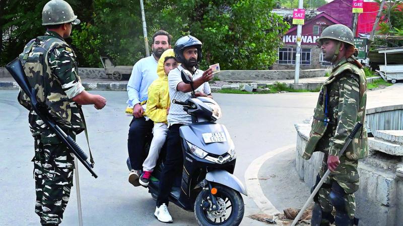 A motorist shows his identity card to security personnel after being stopped for questioning in Srinagar on Tuesday (Photo: AFP)