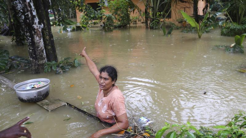 A stranded woman gestures towards her house as she asks for more essential supplies from a volunteer in a flooded area in Chengannur in Kerala. (Photo: AP)