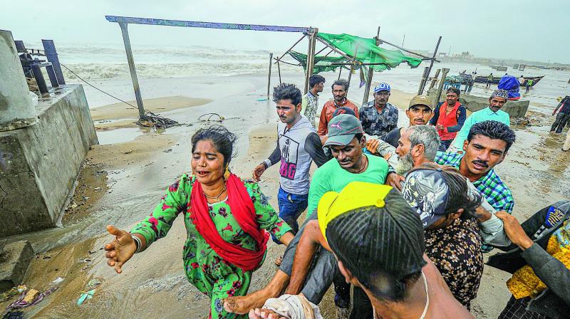 People carry an elderly man who was injured even as strong winds and waves hit the shoreline on Thursday. Gujarat escaped major damage from Cyclone Vayu which swing towards Oman. (PTI)