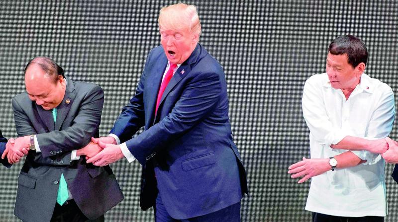 US President Donald Trump, (center), reacts when he realises he is incorrectly doing the  ASEAN-way handshake  on stage in Philippines on Monday.(Photo: AFP)
