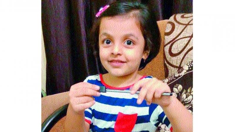 Four-year-old Isha Singh is all smiles using the left-handed sharpener that was specially developed for her. Inset: The left-handed sharpener. (Photo: DC)