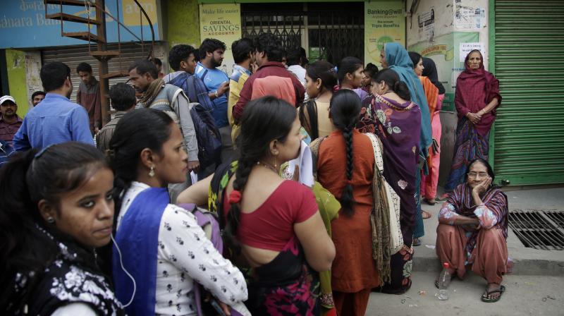 People standing in a queue to deposit and exchange discontinued currency notes outside a bank on the outskirts of New Delhi. (Photo: AP)