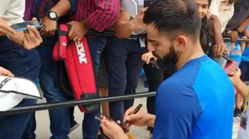 During the training session, Virat Kohli greeted his fans by clicking pictures and signing shirts for his fans and kids who were present in the stands. (Photo: BCCI /screengrab/ Twitter)