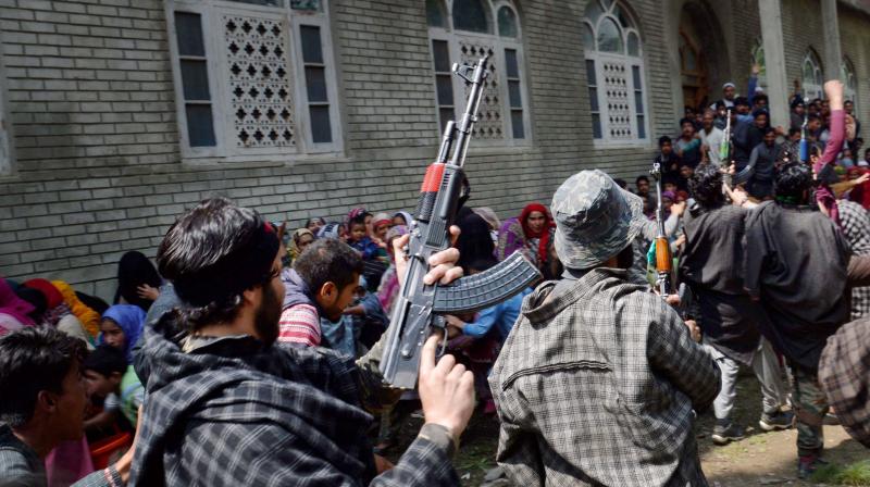 Suspected militants brandish their guns and shout slogans at the funeral of a slain colleague, killed in a shootout with the police, at Qoimoh in Kulgam district of south Kashmir. (Photo: PTI)