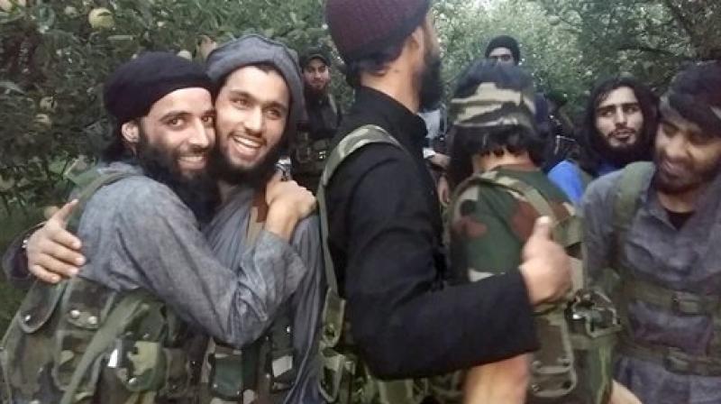 Hizbul Mujahideen Militants greets eachother while displaying weapons which they snatched from police personnel in various attacks, at an apple field in South Kashmir on Wednesday. (Photo: PTI)