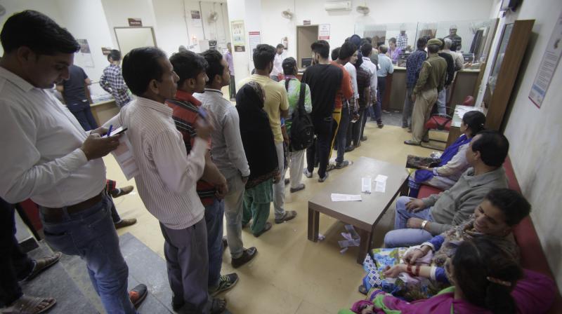People stand in a queue to deposit and exchange discontinued currency notes in Jammu. (Photo: AP)