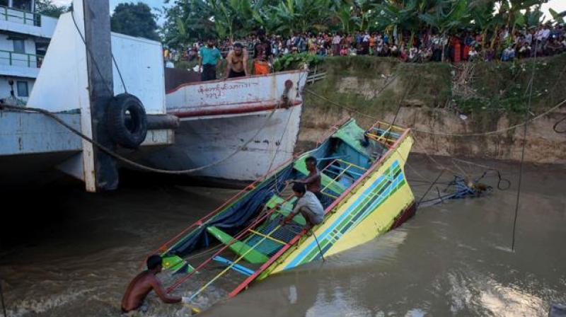 Rescue workers are seen on the sunken ferry partially lifted from the water near the river bank in central Myanmar. The death toll from the ferry disaster four days ago has risen to more than 50, officials said on Wednesday. (Photo: AFP)