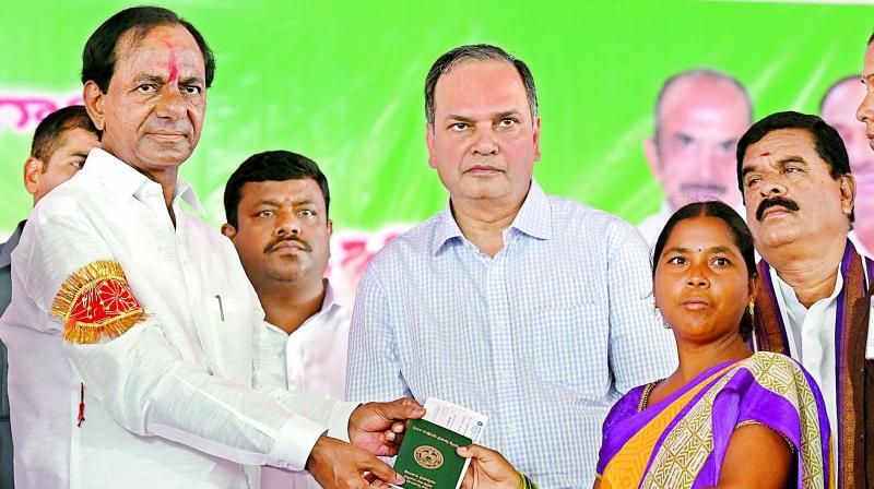 Chief Minister K. Chandrasekhar Rao distributes cheque and pattadar passbook to a farmer in Raithu Bandapathakamat Dharmarajupalli in Huzurabad mandal of Karimnagar district on Thursday. 	(Photo: DECCAN CHRONICLE)