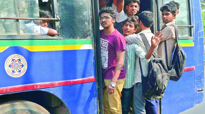 Passengers and students hang on to the footboard of the bus on account of the transport bandh in Vijayawada on Tuesday. (Photo: DC)