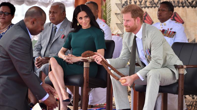 Britains Prince Harry (R) receives a whale tooth necklace as his wife Meghan, Duchess of Sussex (C) looks on during a farewell ceremony at Nadi airport on October 25, 2018.(Photo: AFP)