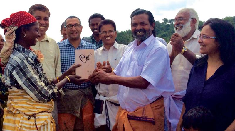 Noted farmer Cheruvayal Raman (third from right) releases the book written by Uday Hue (second from left) handing over the book to a woman labourer in a paddy field at Panamaram, Wayanad on Friday.