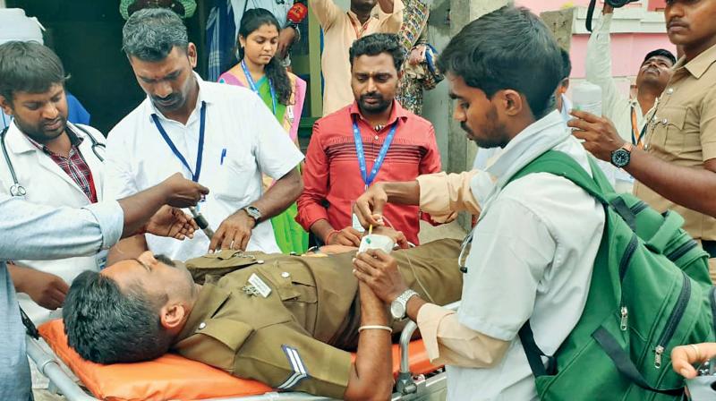 Head constable Senthil Kumar, who fainted on temple premises, getting first aid. (Photo: DC)