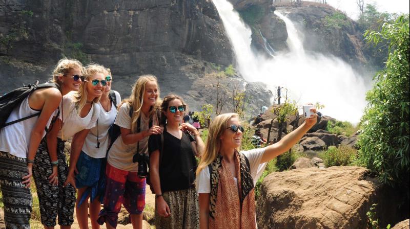 Tourists from USA taking selfie near Athirappally Waterfalls which has shrunk to two small streams in summer on Thursday. The water now seen in the river  is a result of opening the shutters of Upper Sholayar Dam. (Photo: ANUP K. VENU)