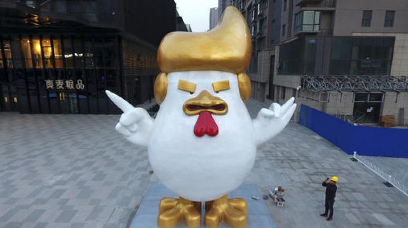A worker takes a picture of a giant rooster sculpture resembling U.S. President-elect Donald Trump on display outside a shopping mall to celebrate the upcoming Chinese Year of the Rooster in Taiyuan. (Photo: AP)