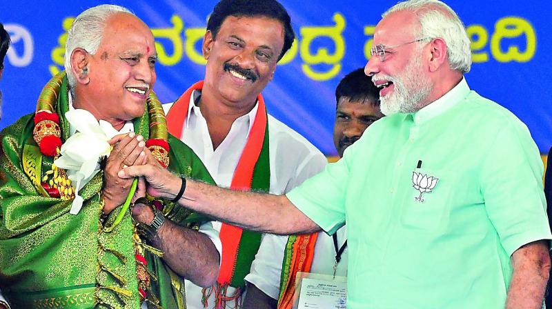 Prime Minister Narendra Modi and BJPs chief ministerial candidate B.S. Yeddyurappa share a lighter moment during Karnataka election campaign rally at Chamarajanagar on Tuesday.(Photo: PTI)