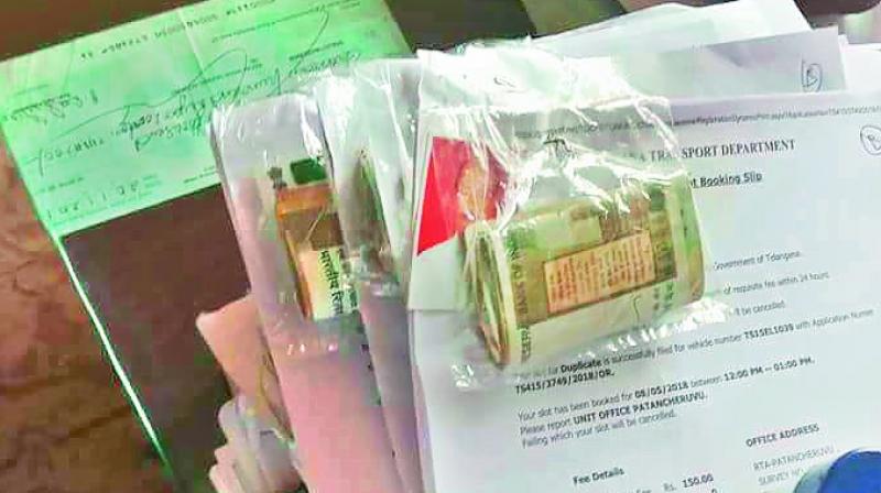 Applications found lying on the table at the RTO office in Patancheru with  bundles of cash in a plastic cover pinned to the. (Photo: DC)