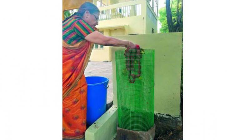 A resident uses a green-netted basket which attracts people and creates awareness regarding composting.