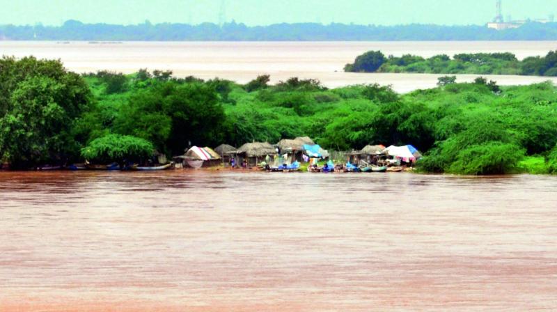 Houses are submerged in flood water at an islet with river Godavari in spate in Rajahmundry on Friday. Around 14.59 lakh cusecs of flood water was released into Bay of Bengal. 	 DC