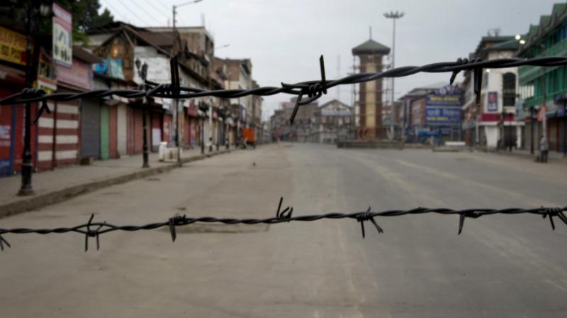 In this August 6, 2019 file photo, a deserted street is seen through a barbwire set up as blockade during curfew in Srinagar. (Photo: AP)