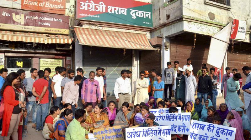 Local residents along with Congress party workers holding a demonstration demanding for removal of a liquor shop. (Photo: PTI)