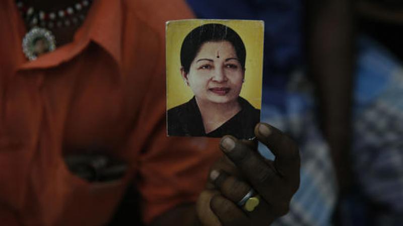 A supporter of Indias Tamil Nadu state Chief Minister Jayaram Jayalalithaa displays her photograph at their party office in Mumbai, India, Monday. (Photo: AP)