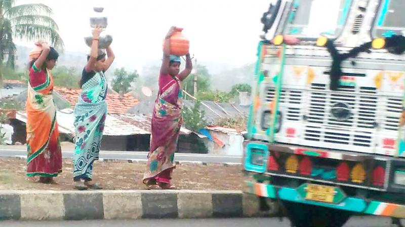 Women of Ganeshnagar cross the NH-44 to return to their village after collecting water in pots from Sainagar village in Gudihathnoor mandal in Adilabad district.