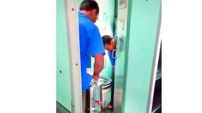 A screenshot from the video that shows two railway tea vendors filling their cans with toilet water.