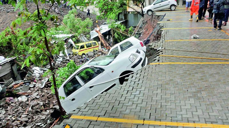 A dislodged car at the site where a portion of the compound wall of a housing society collapsed on shanties in Punes Kondhwa area on Saturday.  (PTI)