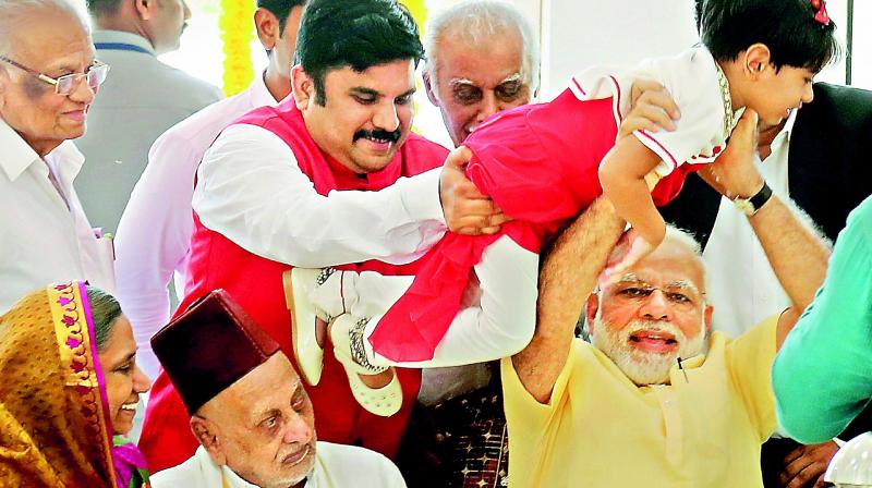 Prime Minister Narendra Modi holds a child while meeting family members of former President A.P.J Abdul Kalam during the inauguration of a memorial at Peikarumbu in Rameswaram, Tamil Nadu, on Thursday. Kalams elder brother Mohammed Muthu Meera Lebbai Maraicker is seen to his right.  (Photo: PTI)