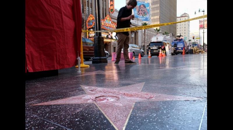A man stands near a cordoned off area surrounding the vandalized star for Donald Trump on the Hollywood Walk of Fame. (Photo: AP)