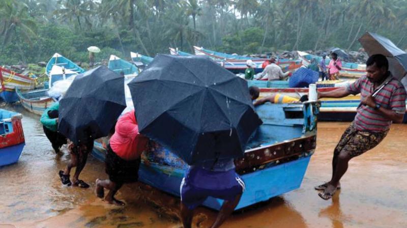 A file picture shows fishermen pulling their boats to safety following cyclone in Thiruvananthapuram.