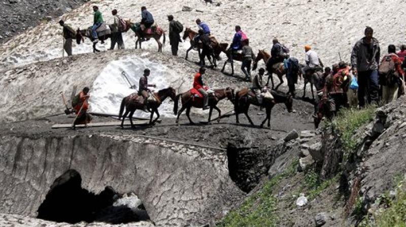 Pilgrims cross mountain trails during their religious journey to the Amarnath cave on the Baltal route, some 125 kms away from Srinagar on Saturday. (Photo: PTI)
