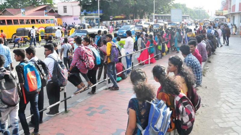 Passengers wait for the bus in front of Thampanoor central bus stand in Thiruvananthapuram on Monday. (Photo: DC)