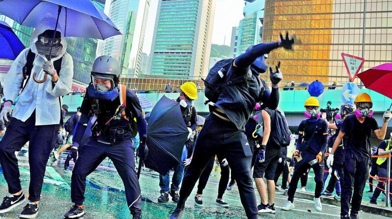 An anti-government protester throws a rock near Central Government Complex in Hong Kong on Sunday. (Photo: AP)