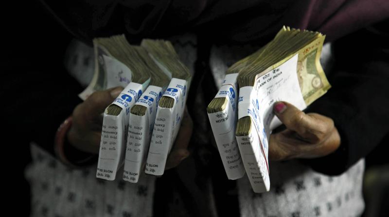 A cashier holds bundles of Indian currency notes at a bank in Allahabad. (Photo: AP)
