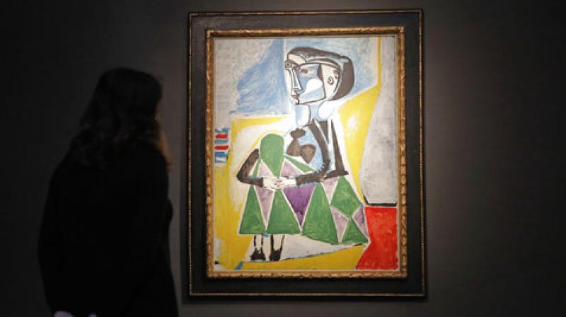 A Christies auction house staff member poses for photographs in front of the 1954 Pablo Picasso painting \Femme accroupie (Jacqueline)\, a portrait of Jaqueline Roque, Picassos final great muse and eventually his second wife, at their premises in London, Wednesday, Sept. 13, 2017. (Photo: AP)