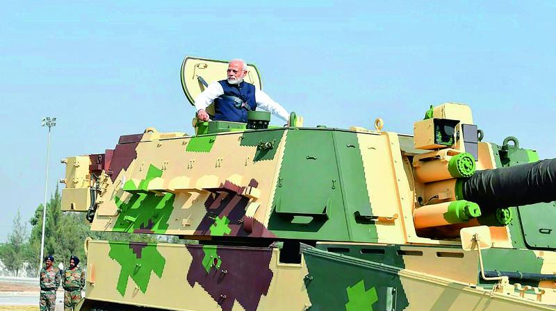 Prime Minister Narendra Modi rides a K-9 Vajra Self-Propelled Howitzer built by Larsen & Toubro after the dedication of L&Ts Armoured System Complex to the nation, in Hajira, Saturday. (PTI)