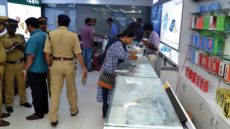 Police and fingerprint experts collect clues from the mobile phone shop in Thampanoor on Thursday. 	(Photo: DC)