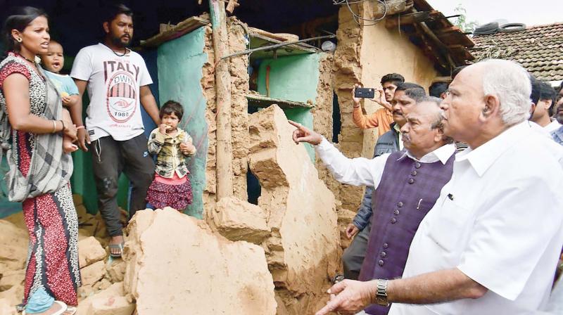 Chief Minister B.S. Yediyurappa speaks to family members whose house was damaged in rain a few days ago in Shivamogga on Tuesday  (Photo:PTI)