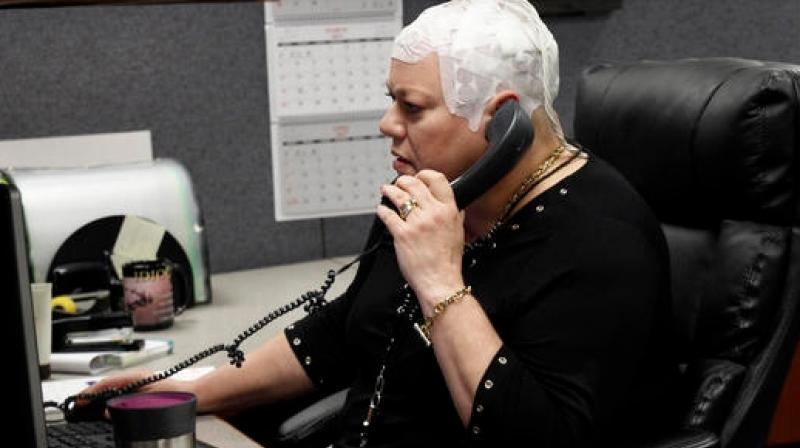 In this March 29, 2017 photo, Joyce Endresen wears an Optune therapy device for brain cancer, as she speaks on a phone at work in Aurora, Ill. She was diagnosed in December 2014 with Glioblastoma.  (Photo: AP)