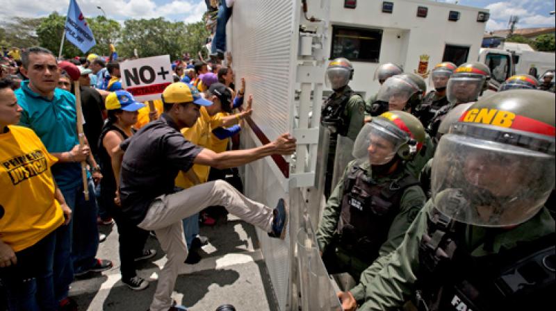 Opposition members kick and push a Venezuelan Bolivarian National Guard barricade during a protest in Caracas, Venezuela. (Photo: File/AP)