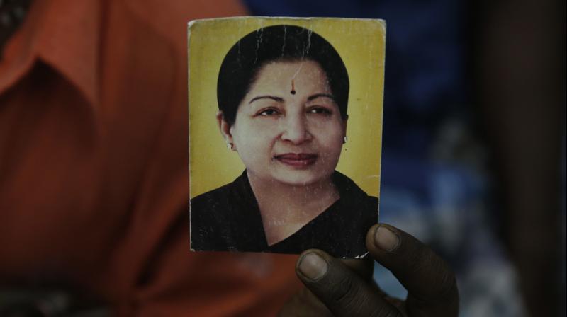 A supporter of Indias Tamil Nadu state Chief Minister Jayaram Jayalalithaa displays her photograph at their party office in Mumbai, India (Photo: AP)