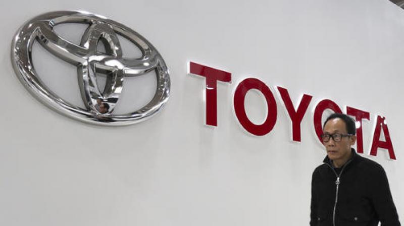 A visitor walks past the logo of Toyota Motor Corp. at its showroom. (Photo: AP)